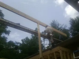 Carpenter setting a ridge beam over a new addition frame — Ice Dam Removal by Roofing Brothers in Douglassville