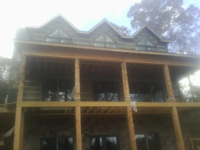 Dormers and porch framing on a large log home under construction — Roof Coating work by our crew in Douglassville