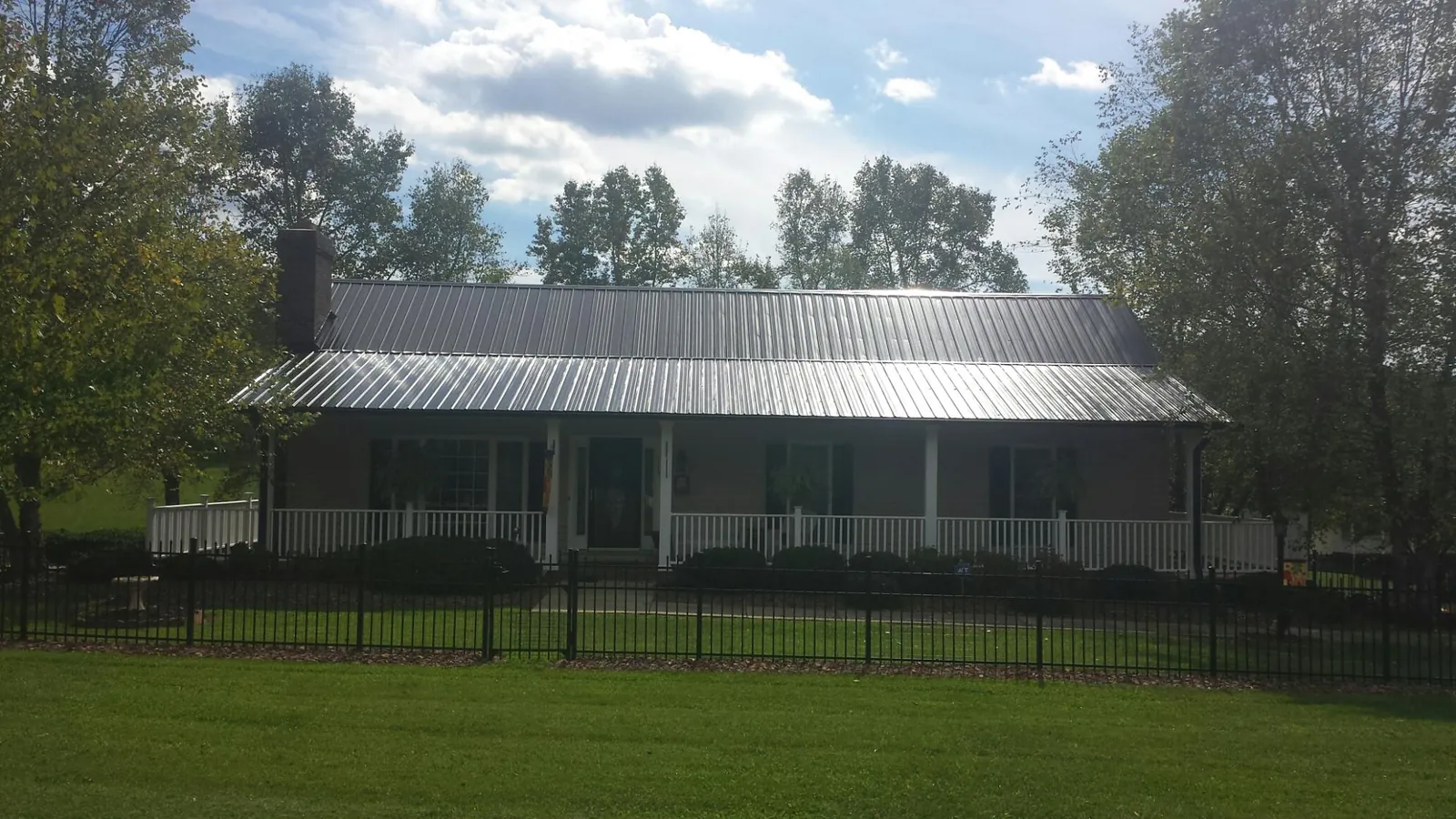 Gray metal roof on a brick ranch with a full width front porch — Gutter Guard Installation work by our crew in Douglassville