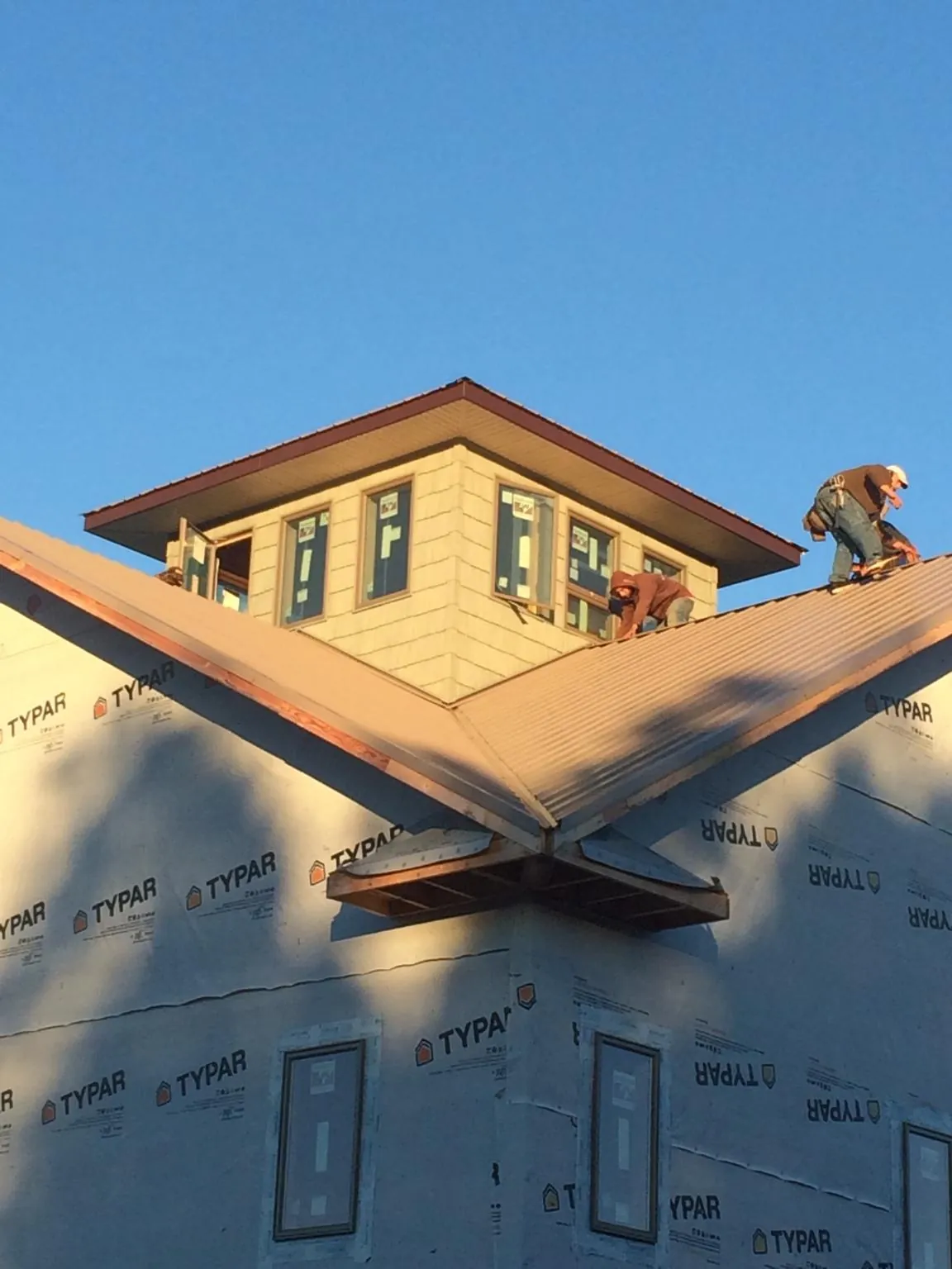 Roofers working around a rooftop cupola on a new metal roof at sunset — Roof Waterproofing in Douglassville by Roofing Brothers